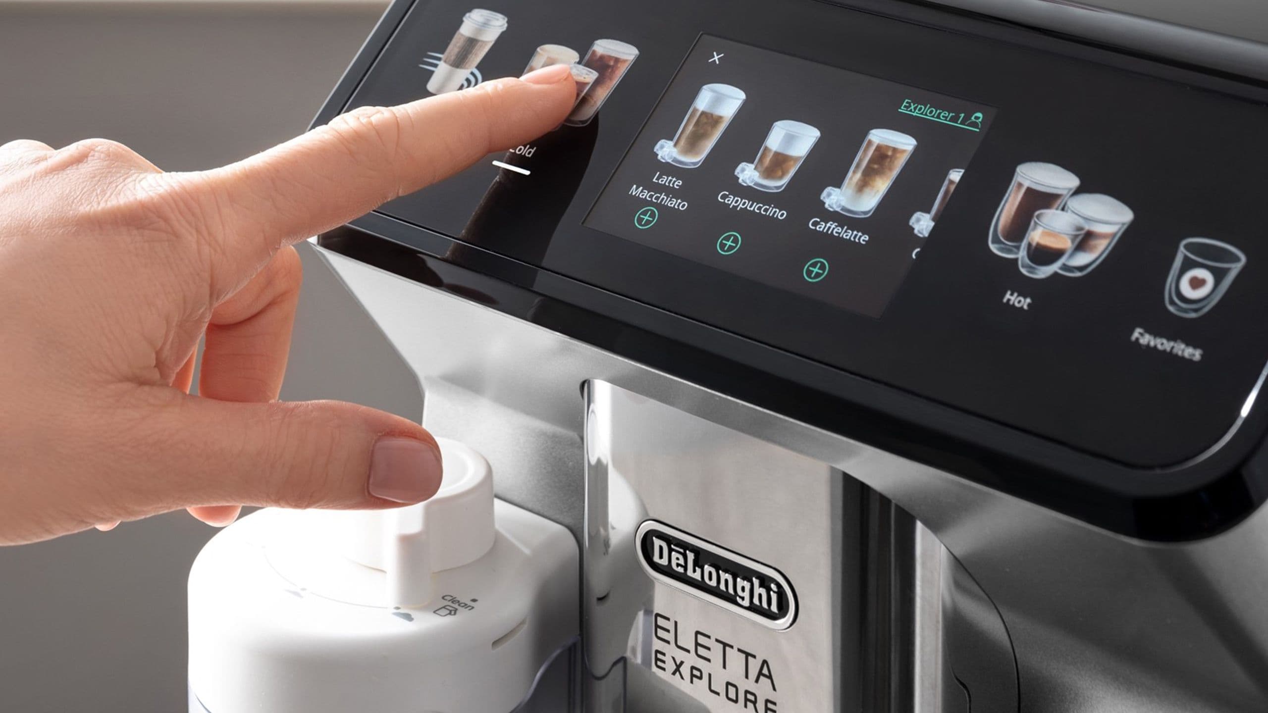 Jemand drückt mit dem Zeigefinger auf das Touch-Display eines Kaffeevollautomaten von De'Longhi. Es ist das Modell Eletta Explore