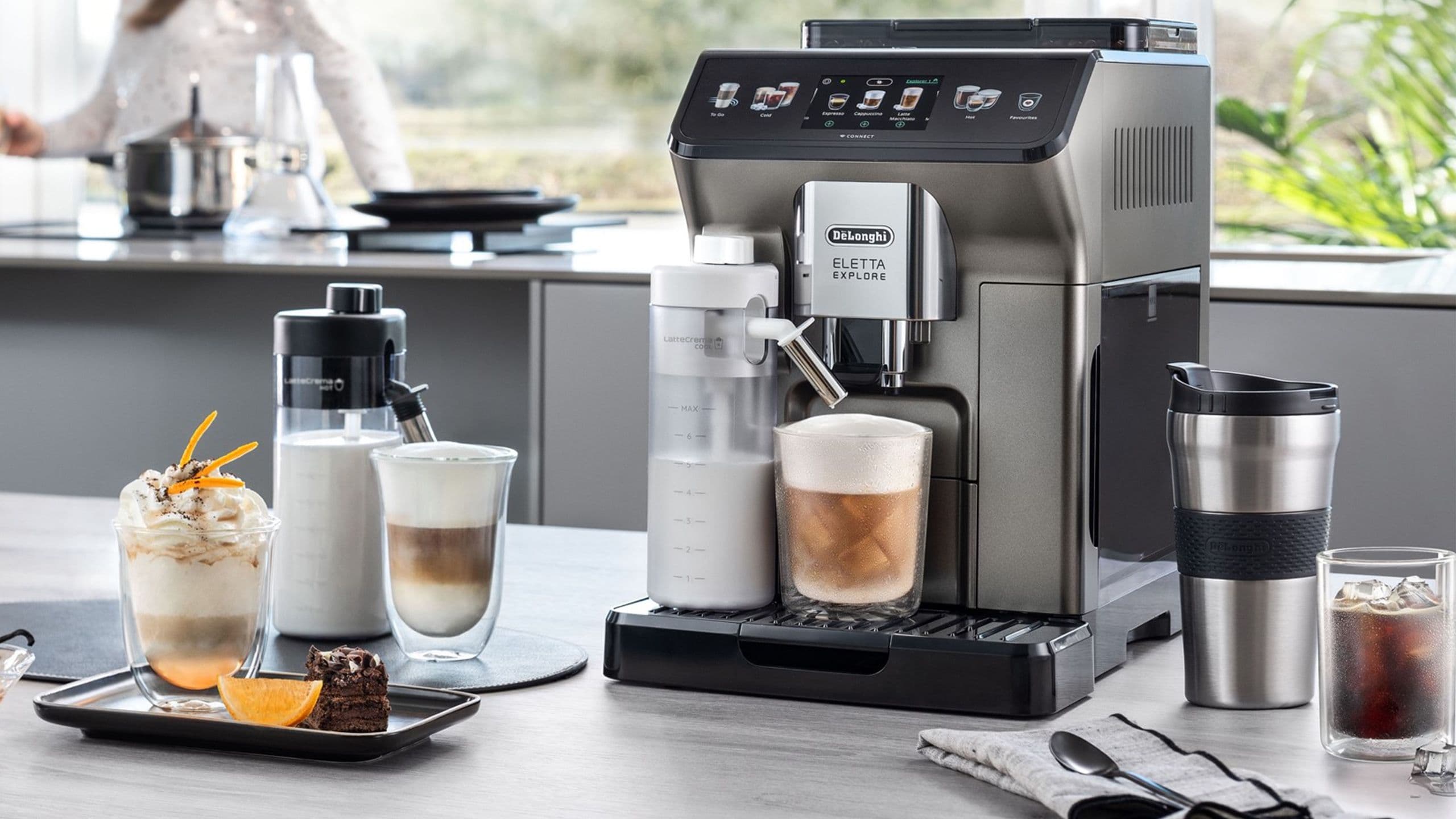 Auf einer grauen Holztischplatte steht ein De'Longhi Kaffeevollautomat, Modell Eletta Explore